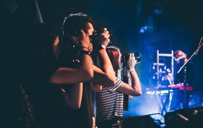 A close-up of three people taking pictures at a concert