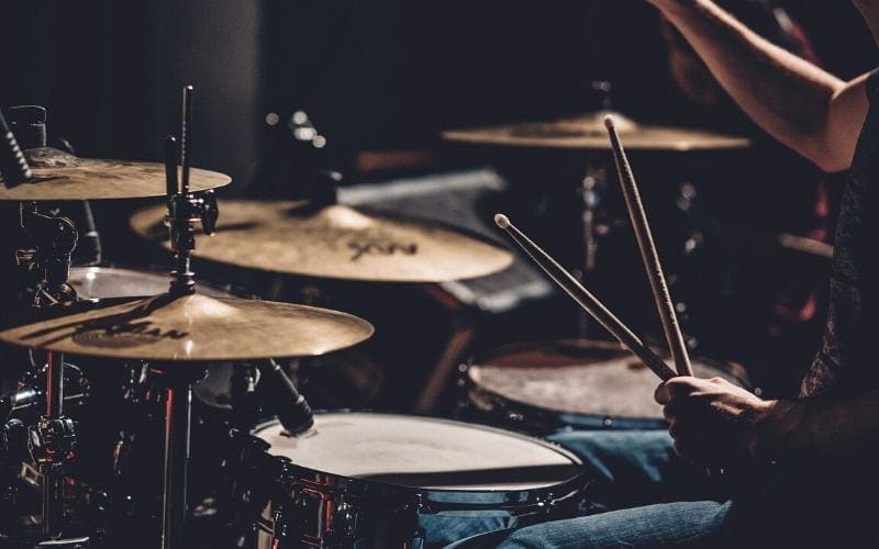 Drummer with 4 cymbals holding drumsticks