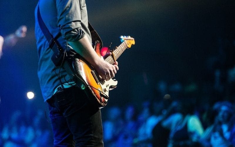 man playing guitar on stage performing