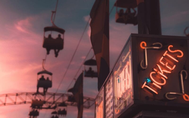 Neon tickets sign with ride in the background.