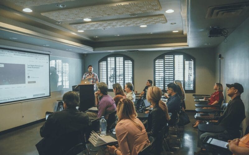 People in a room listening to a presentation and lecture. 