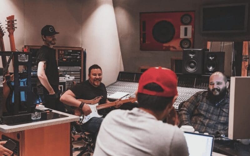 artists in the studio with producer discussing split sheets