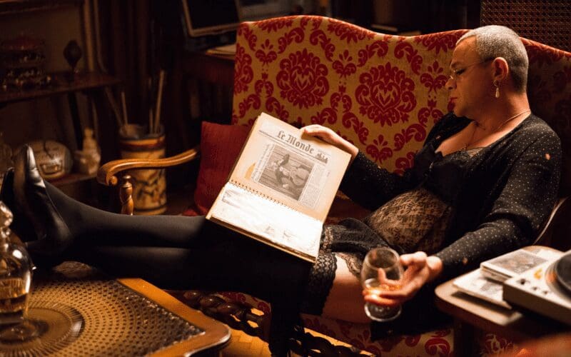 Person relaxing on a sofa reading and having a drink.