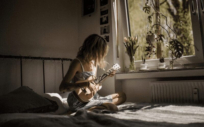 girl learning guitar in bedroom with plants