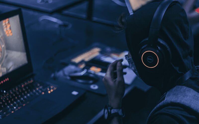 Person using gaming laptop with headphones 