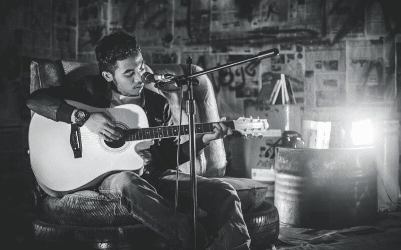 A man playing the guitar and singing into a microphone.