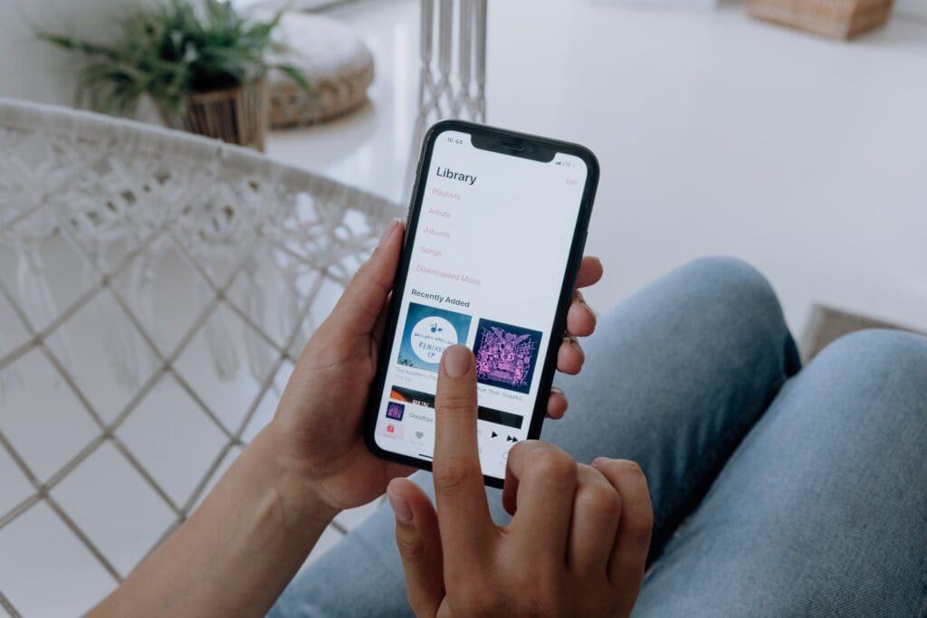 Man wearing blue jeans holds a smartphone and uses Apple.Music Replay App